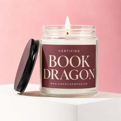 Candle "Certified Book Dragon" from MagicMerchEmporium on pink background.