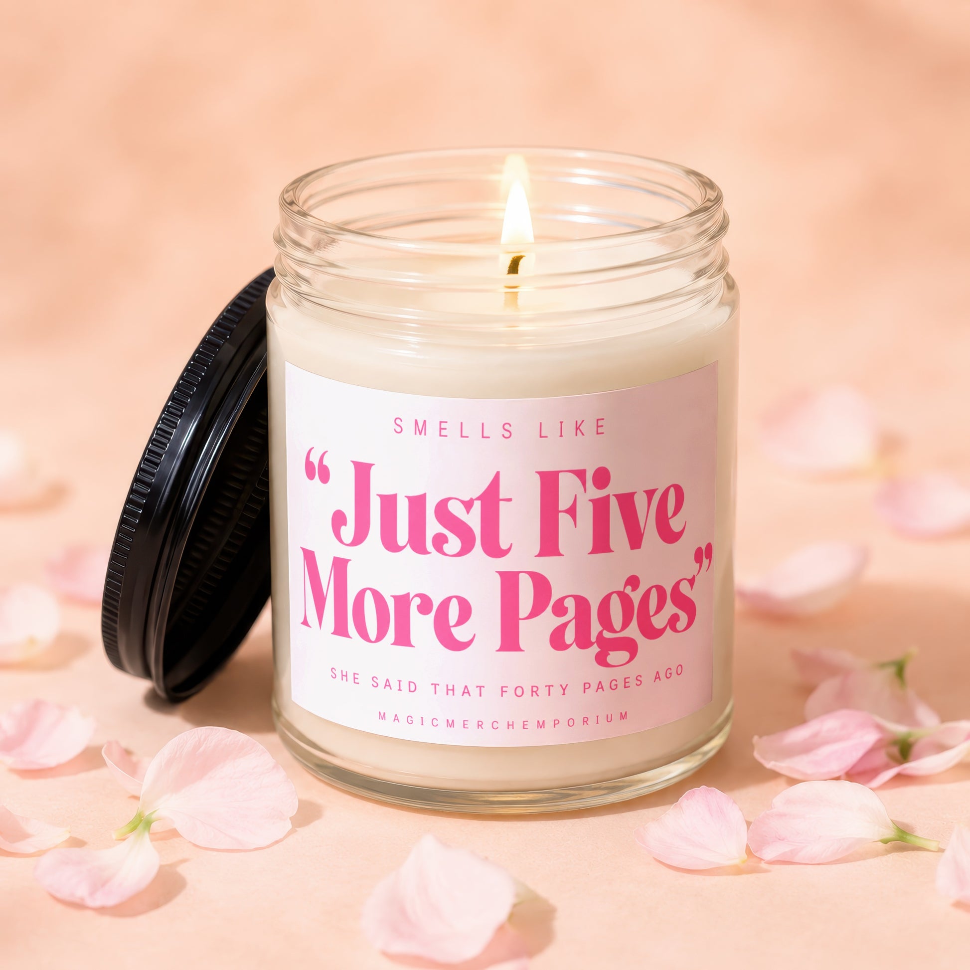 Burning candle in glass jar with pink label reading "Just Five More Pages."