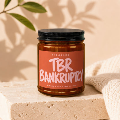 Amber jar candle with a pink label reading "TBR BANKRUPTCY" and "MAGICMERCHMEPOTRIUM".