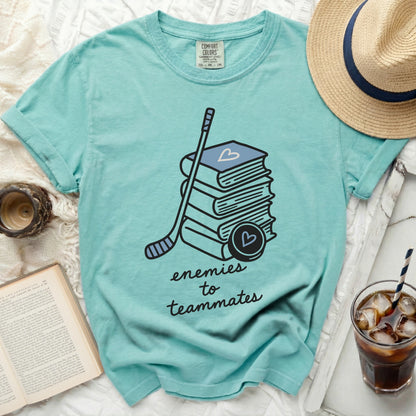 Teal t-shirt with stack of books, hockey stick, and puck, "enemies to teammates" text.