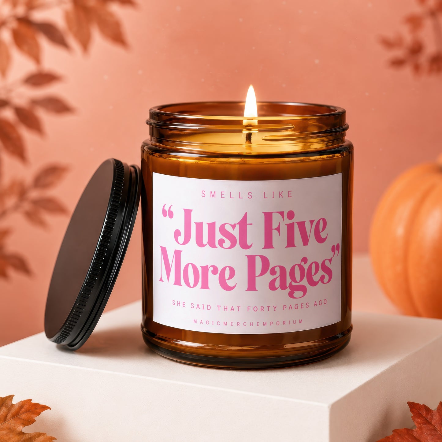 Amber candle with pink text "Just Five More Pages" in a fall-themed setting.
