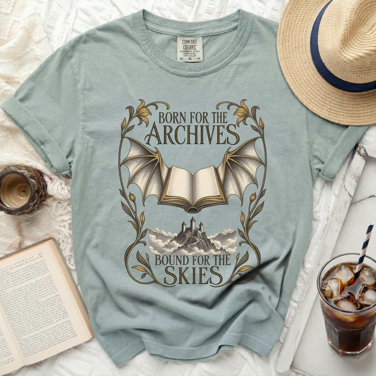 Dusty blue t-shirt with "Born for the Archives, Bound for the Skies" text and batwing book graphic.