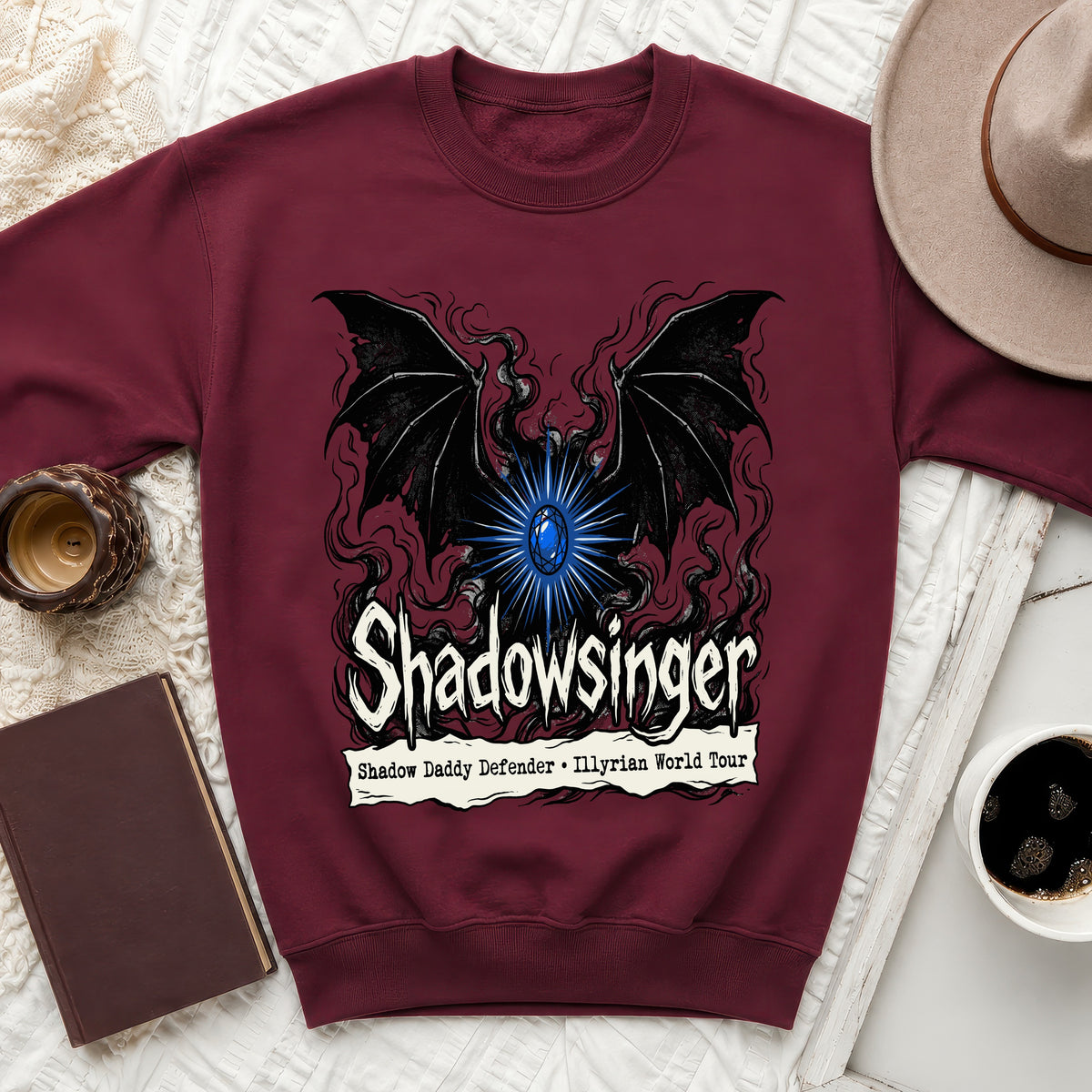 Maroon crewneck sweatshirt featuring a graphic with bat wings, a blue gem, and text reading "Shadowsinger Shadow Daddy Defender Illyrian World Tour".