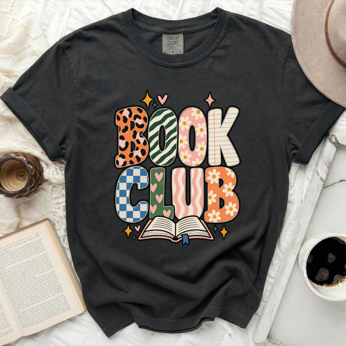 Dark gray Comfort Colors t-shirt with "BOOK CLUB" in colorful, patterned letters.