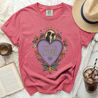 Pink Comfort Colors t-shirt with "To Be Loved" graphic and romantic couple silhouette.