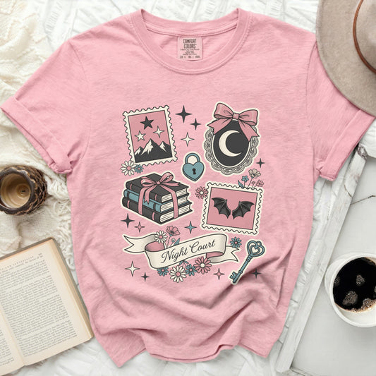 Pink t-shirt with "Night Court" banner and whimsical celestial and book-themed graphics.