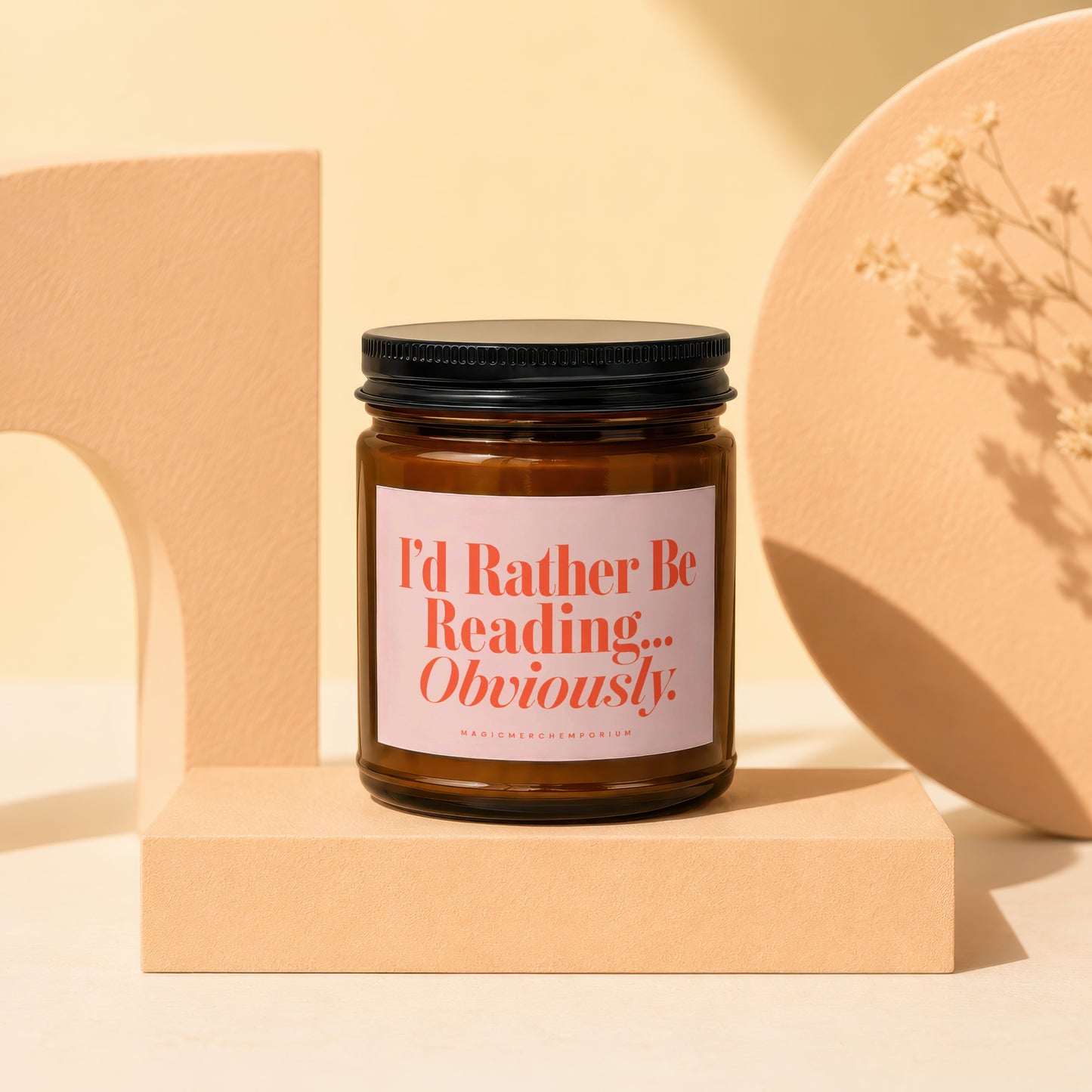 Amber glass candle with a pink label reading "I'd Rather Be Reading... Obviously."