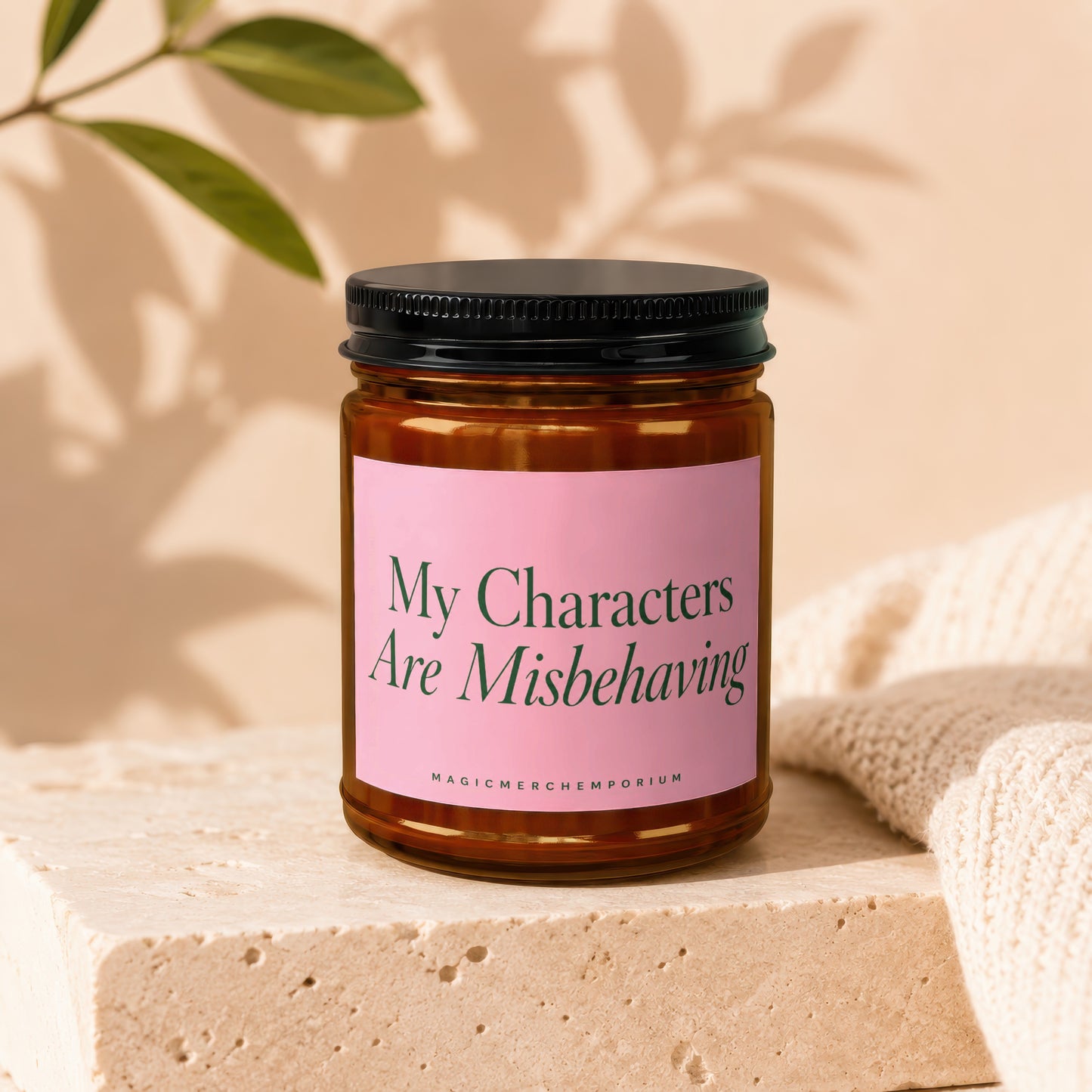 Glass candle with pink label reading "My Characters Are Misbehaving".