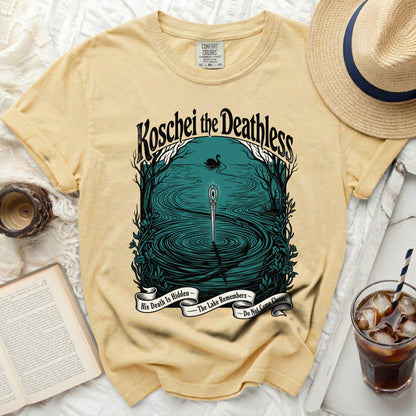 Yellow t-shirt with a graphic of Koschei the Deathless, a swan, and a sword in a lake.