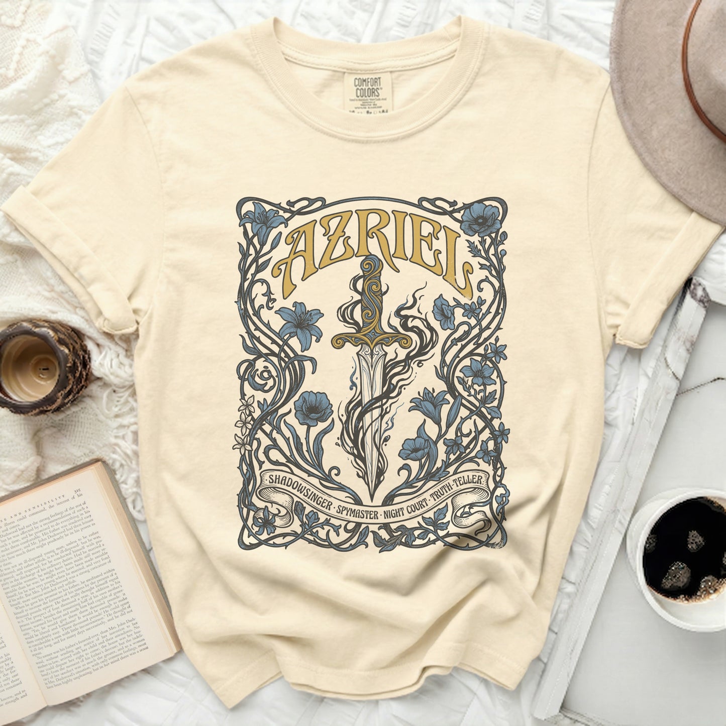 Cream t-shirt with floral sword design and "AZRIEL" text.