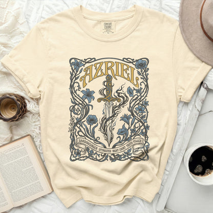 Cream t-shirt with floral sword design and "AZRIEL" text.