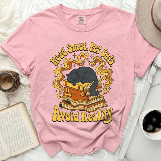 Pink t-shirt with graphic of black cat sleeping on books, "Read Smut. Pet Cats. Avoid Reality."