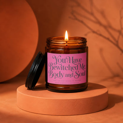 Amber jar candle with pink label reading "You Have Bewitched Me, Body and Soul"