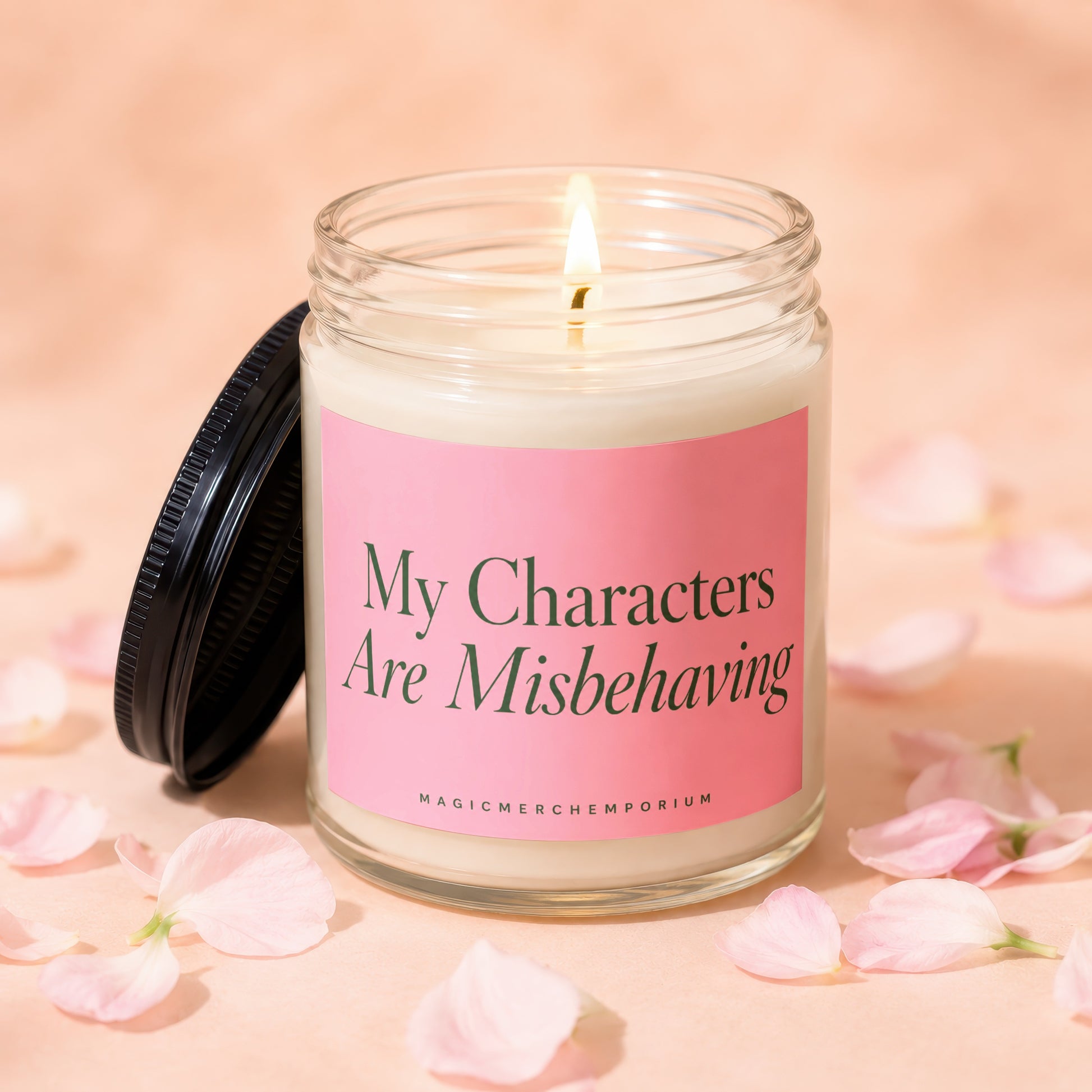 Candle with lit wick and pink label reading "My Characters Are Misbehaving".