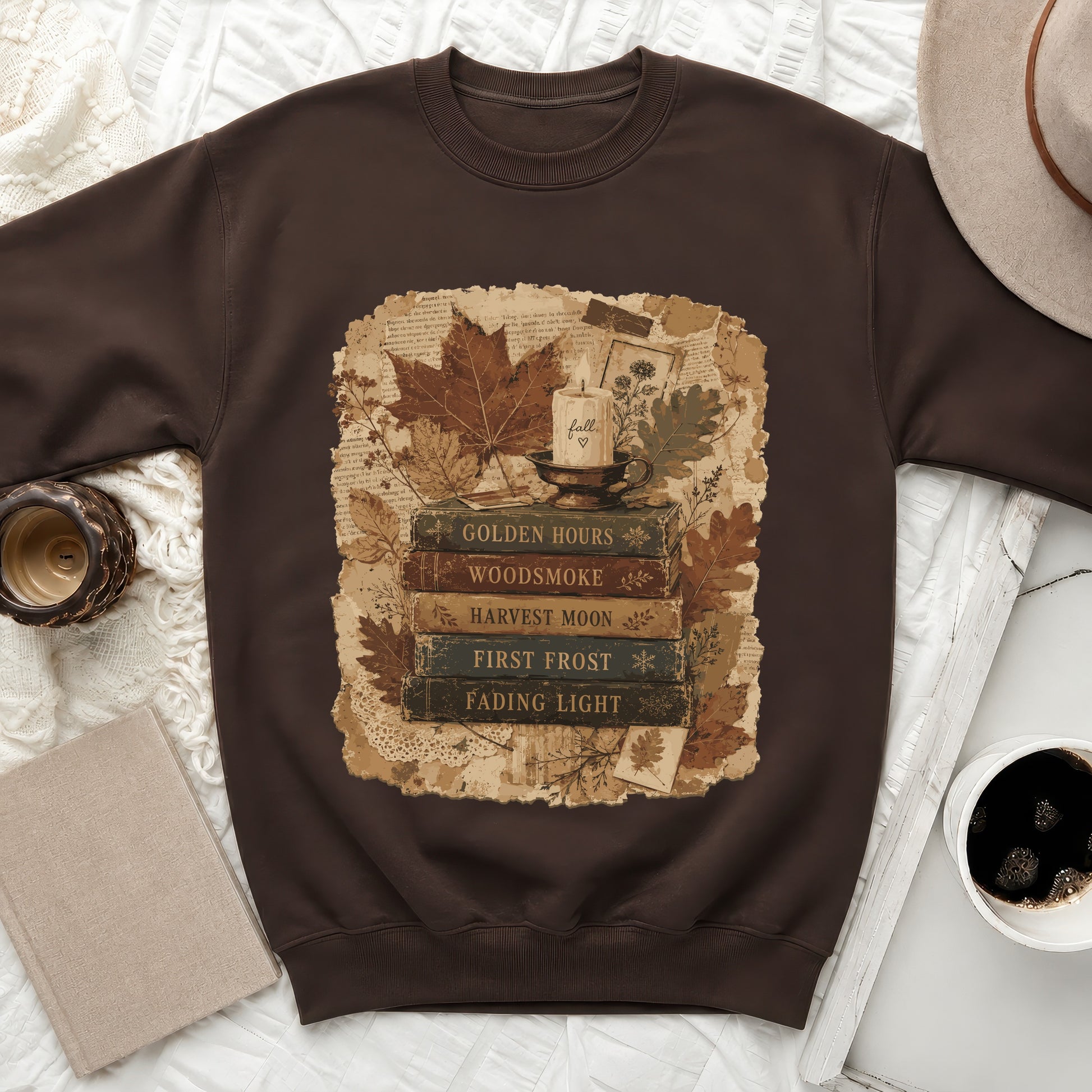 Brown sweatshirt with a vintage book stack, candle, and autumn leaves graphic.