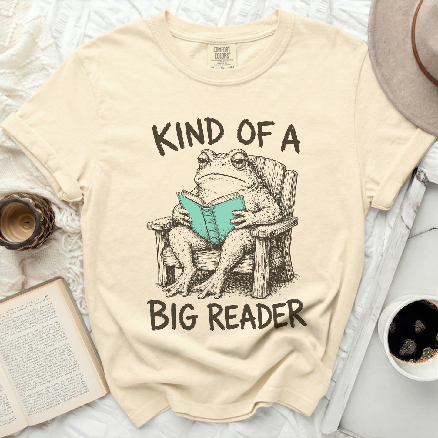 T-shirt with a toad in a chair reading a book.