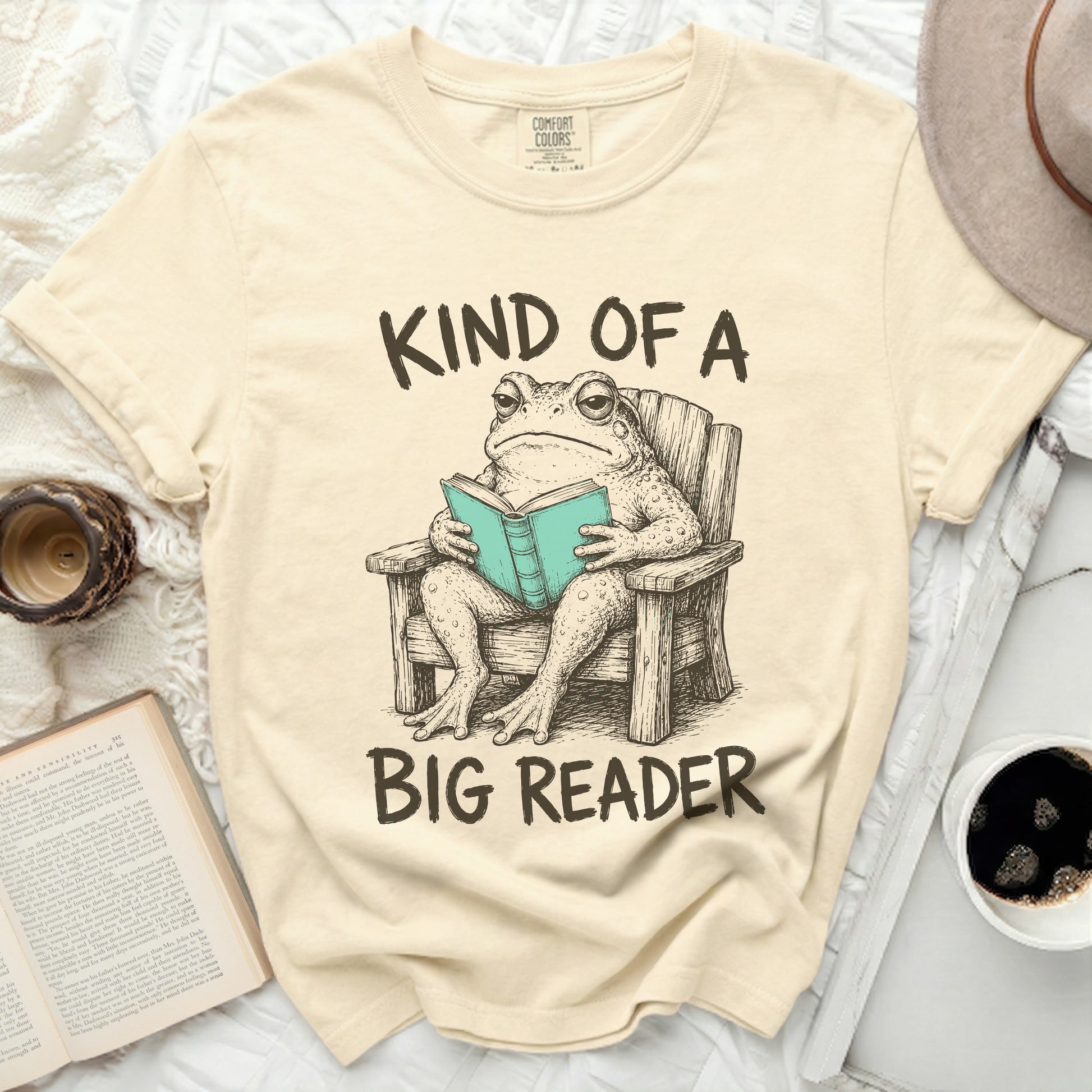 T-shirt with a toad in a chair reading a book.