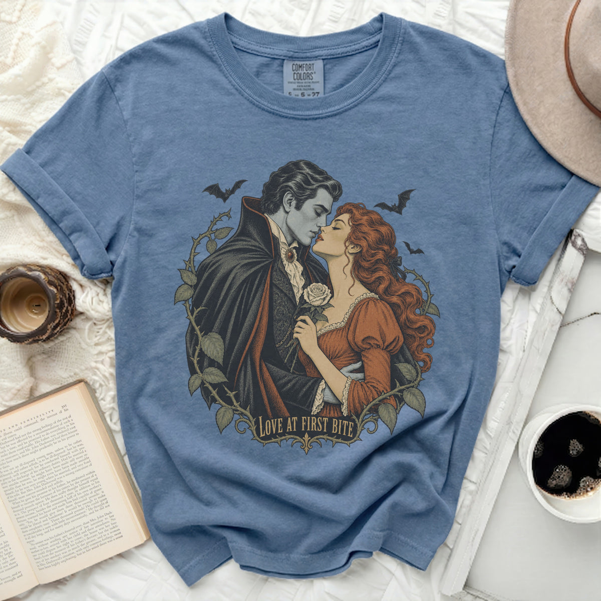 Vampire couple kissing, holding rose, with bats and text "LOVE AT FIRST BITE".