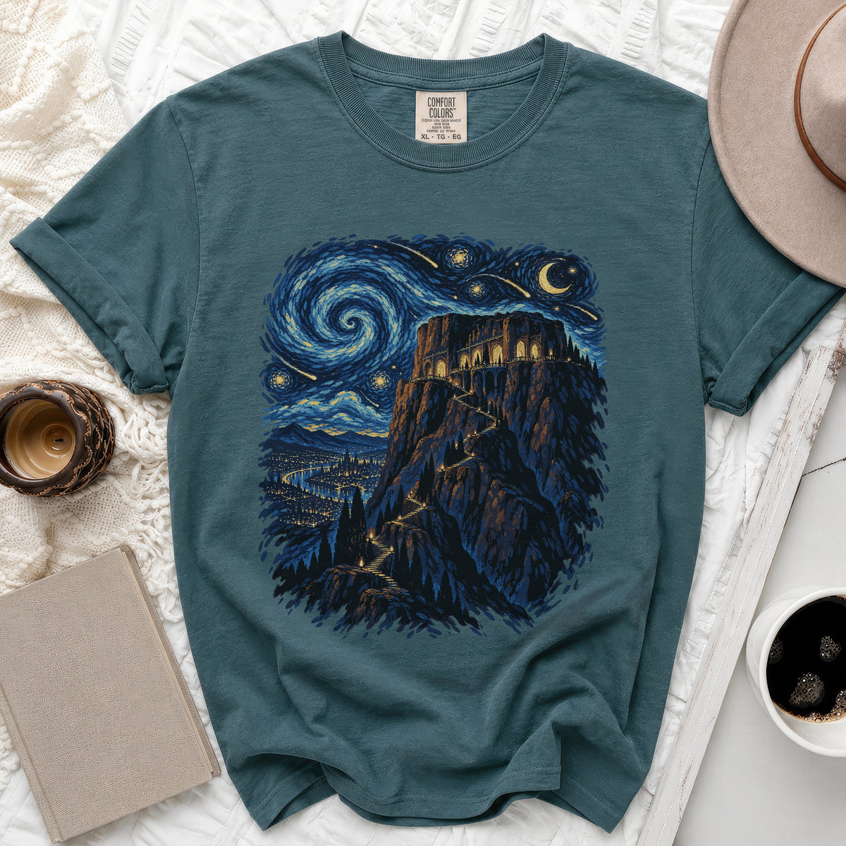 Teal t-shirt with a castle on a mountain under a starry, swirling night sky.
