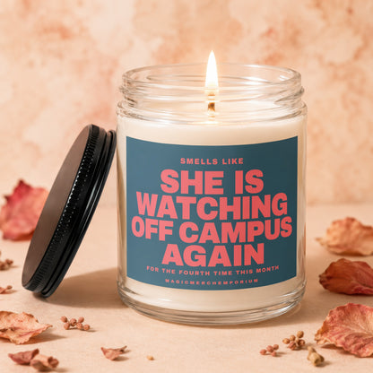 Lit candle with text "Smells Like She Is Watching Off Campus Again" on label.