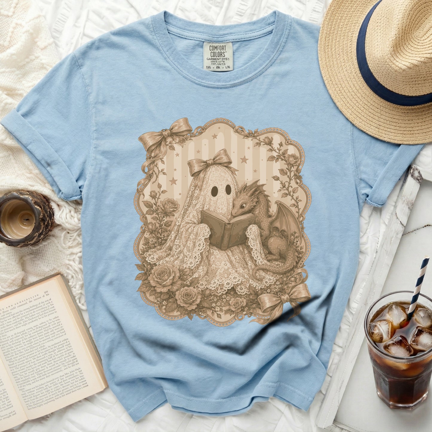 A ghost in a lace dress reads a book with a small dragon beside it.