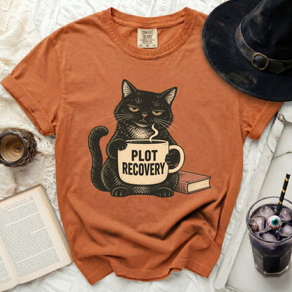 Black cat holding a mug that says "PLOT RECOVERY" next to a book.