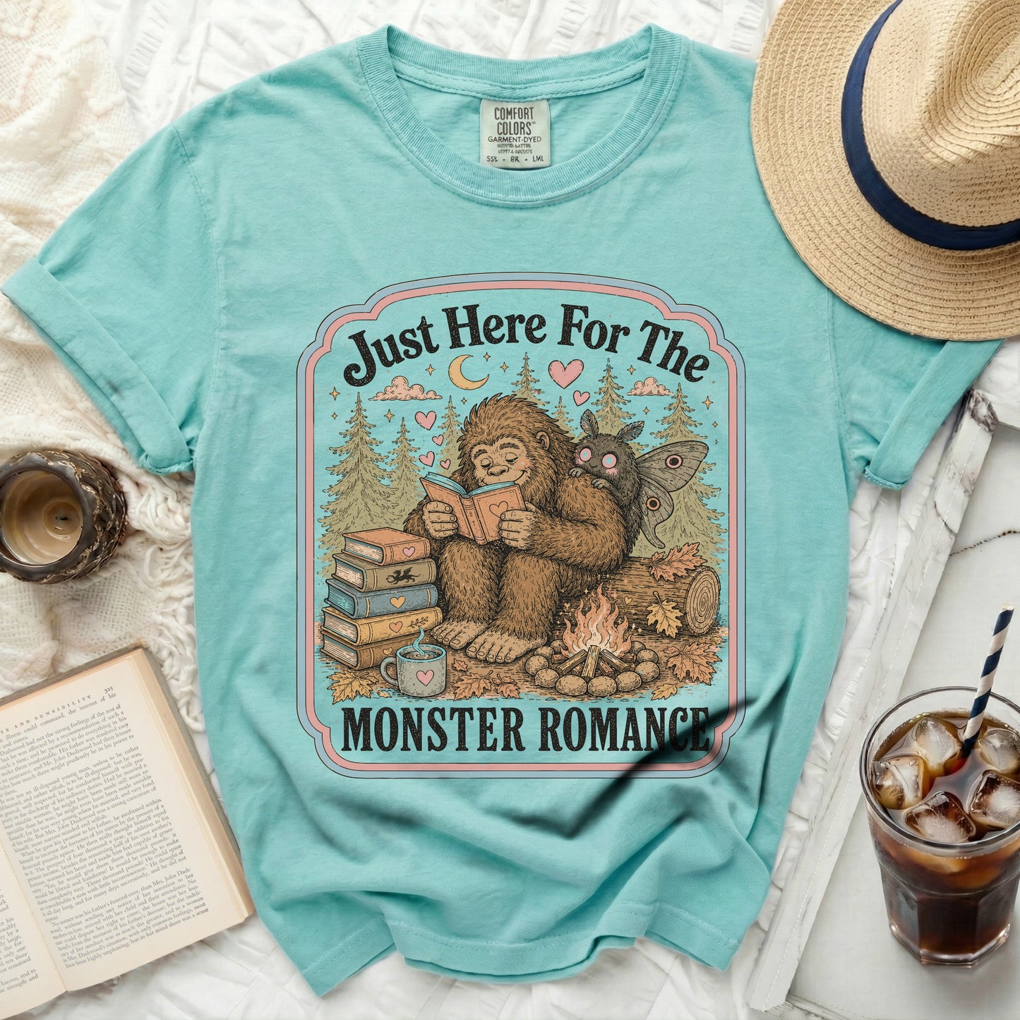 Bigfoot reads to a moth in a forest scene with text "Just Here For The MONSTER ROMANCE".