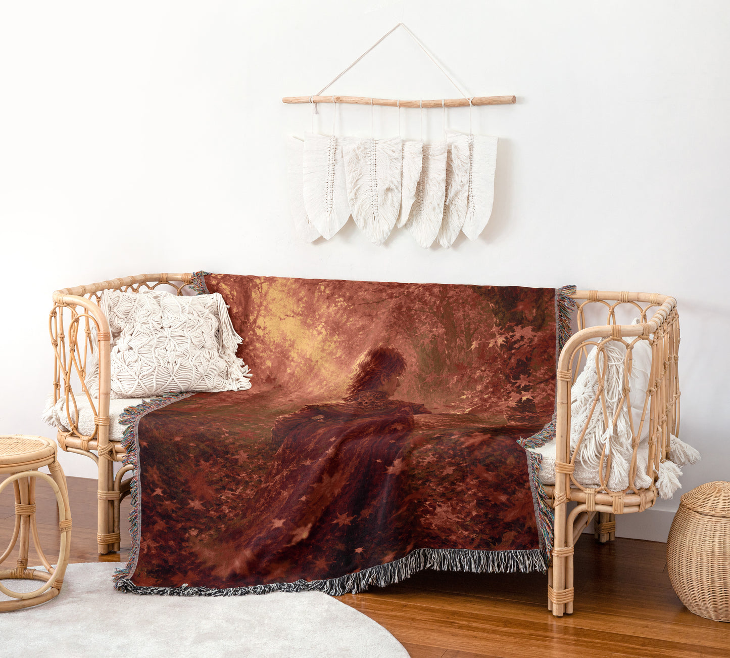 a cozy living room with a woven bench and a large, colorful blanket draped over it. The blanket has a forest scene on it, adding a touch of nature to the space. The room is decorated with a hanging feather wall art piece and a woven basket, creating a warm and inviting atmosphere.