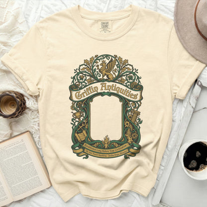 Cream t-shirt with ornate green Griffin Antiquities logo and text.