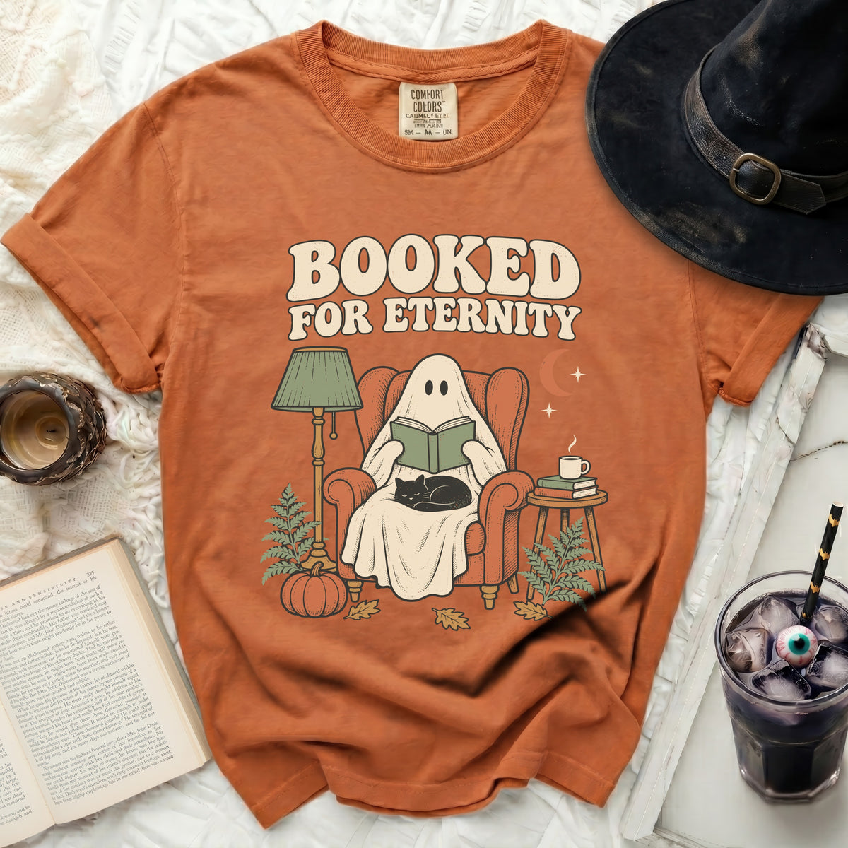 Ghost reading book in chair with cat, text "BOOKED FOR ETERNITY".