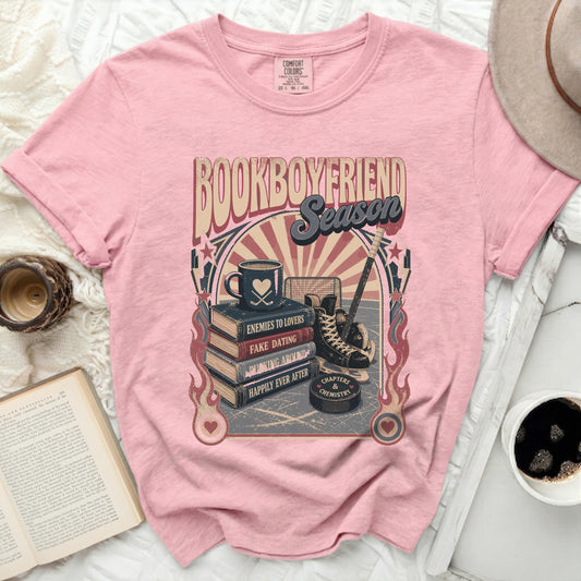 Pink t-shirt with "Bookboyfriend Season" text, stack of books, hockey skates, and puck.