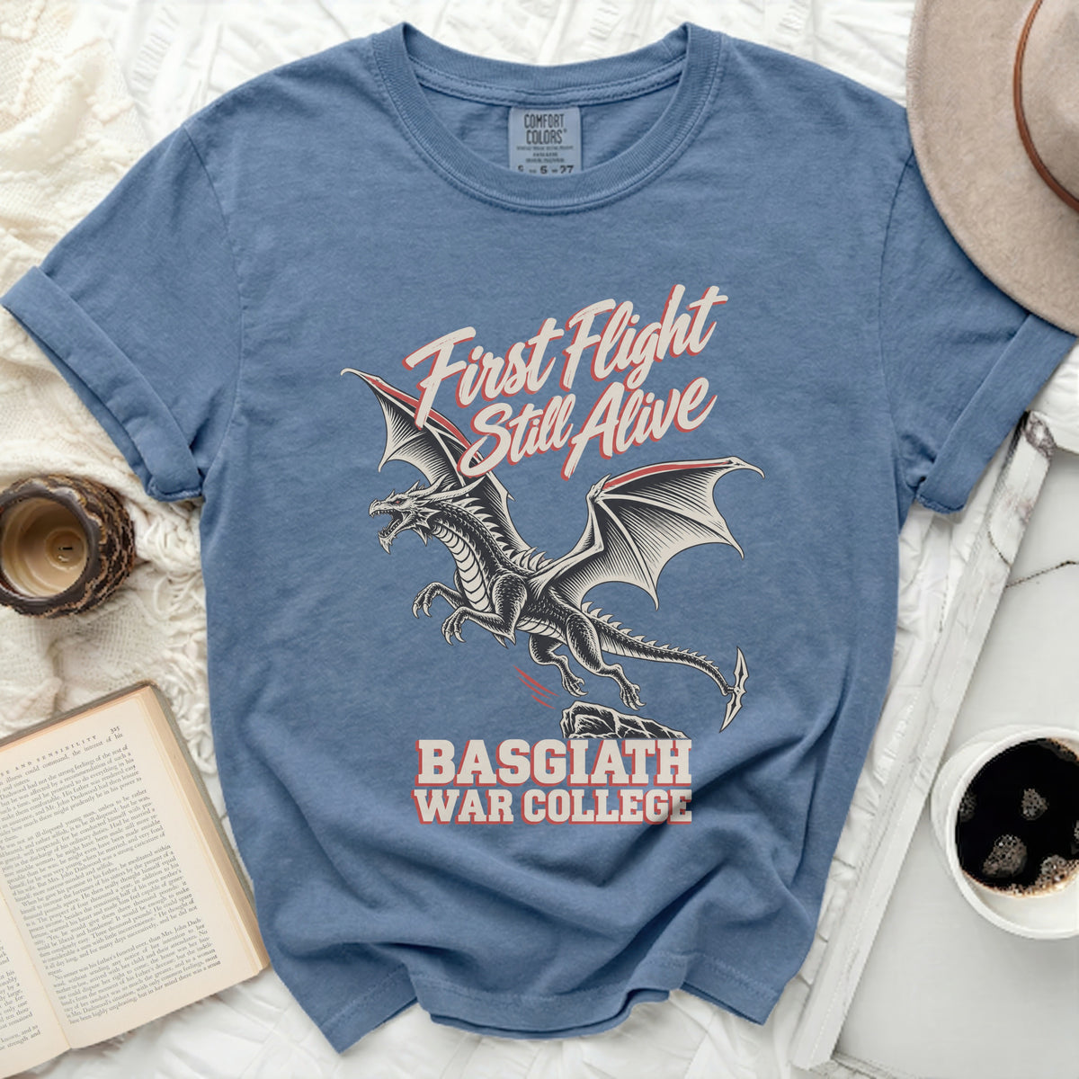 Blue t-shirt with a black dragon graphic and text "First Flight Still Alive" and "Basgiath War College".