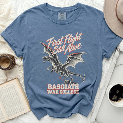Blue t-shirt with a black dragon graphic and text "First Flight Still Alive" and "Basgiath War College".
