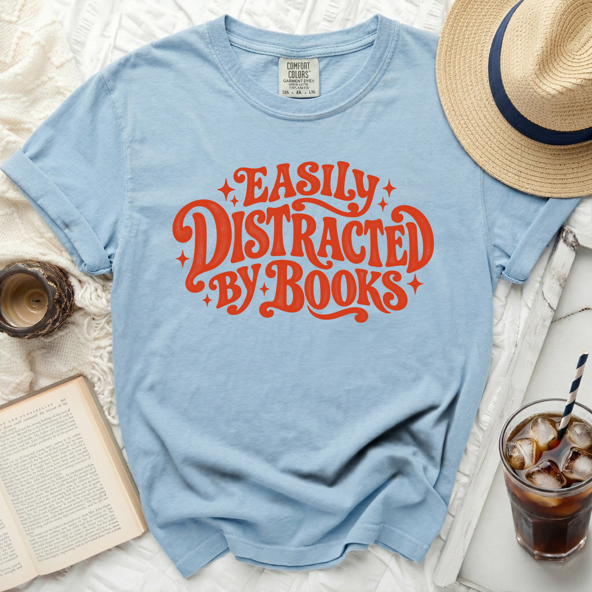 Light blue t-shirt with "Easily Distracted By Books" text in orange.