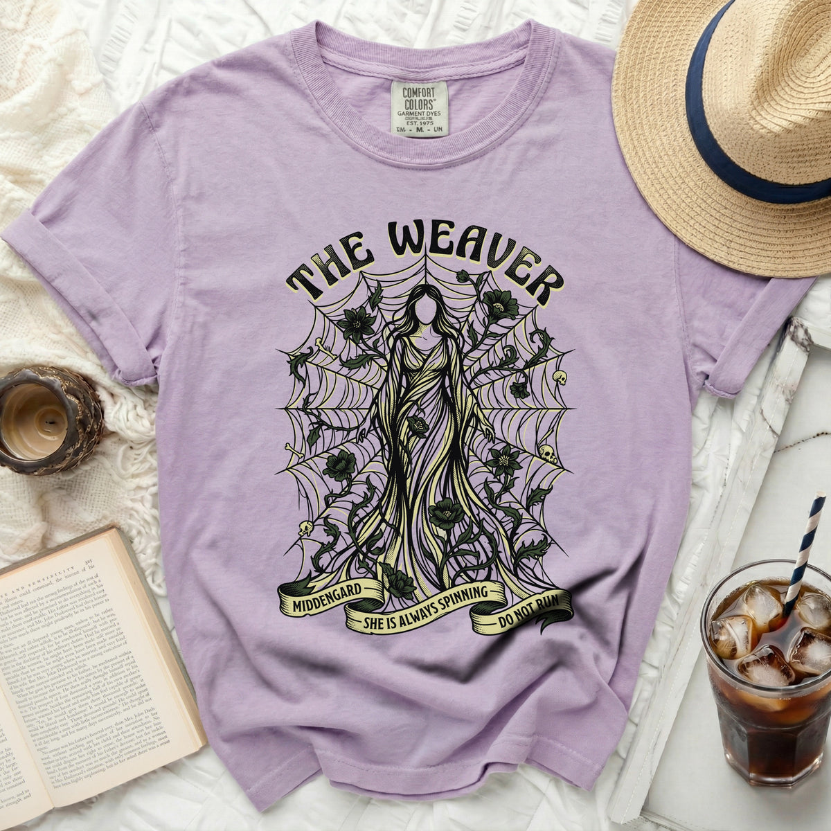 Lavender t-shirt with "The Weaver" graphic and spiderwebs, skulls, and flowers.
