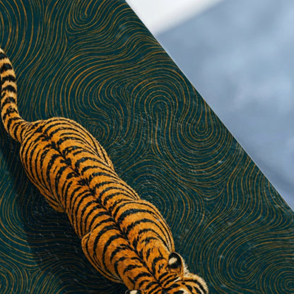 Tiger crawling across a dark teal surface with swirling gold patterns.