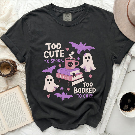 Black t-shirt with "Too Cute to Spook, Too Booked to Care" Halloween graphic.