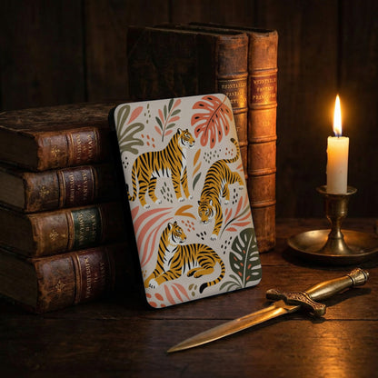 Case with tigers and leaves design beside antique books and lit candle.