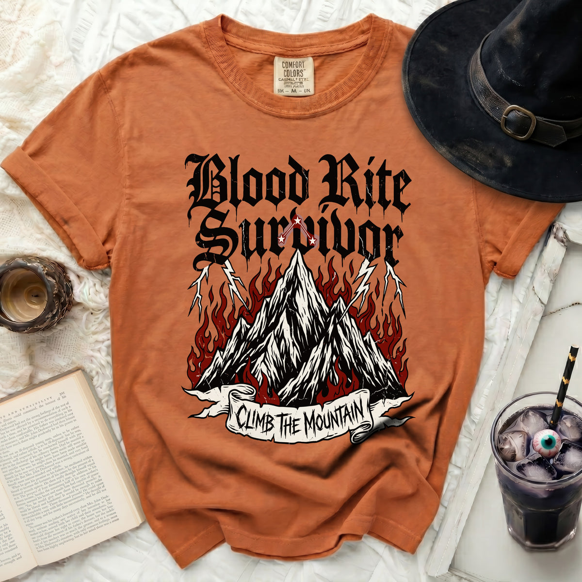 Orange t-shirt with "Blood Rite Survivor Climb The Mountain" graphic and witchcraft elements.
