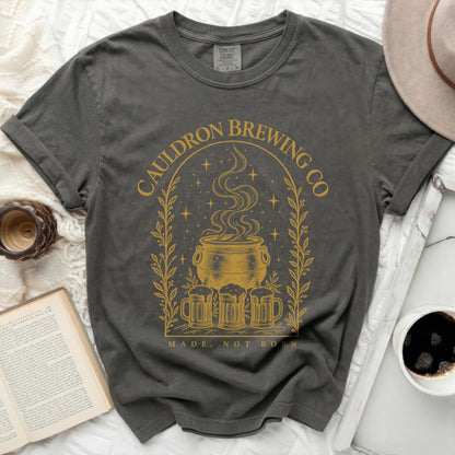 Charcoal gray t-shirt with a gold graphic of a cauldron, beer mugs, stars, and text.