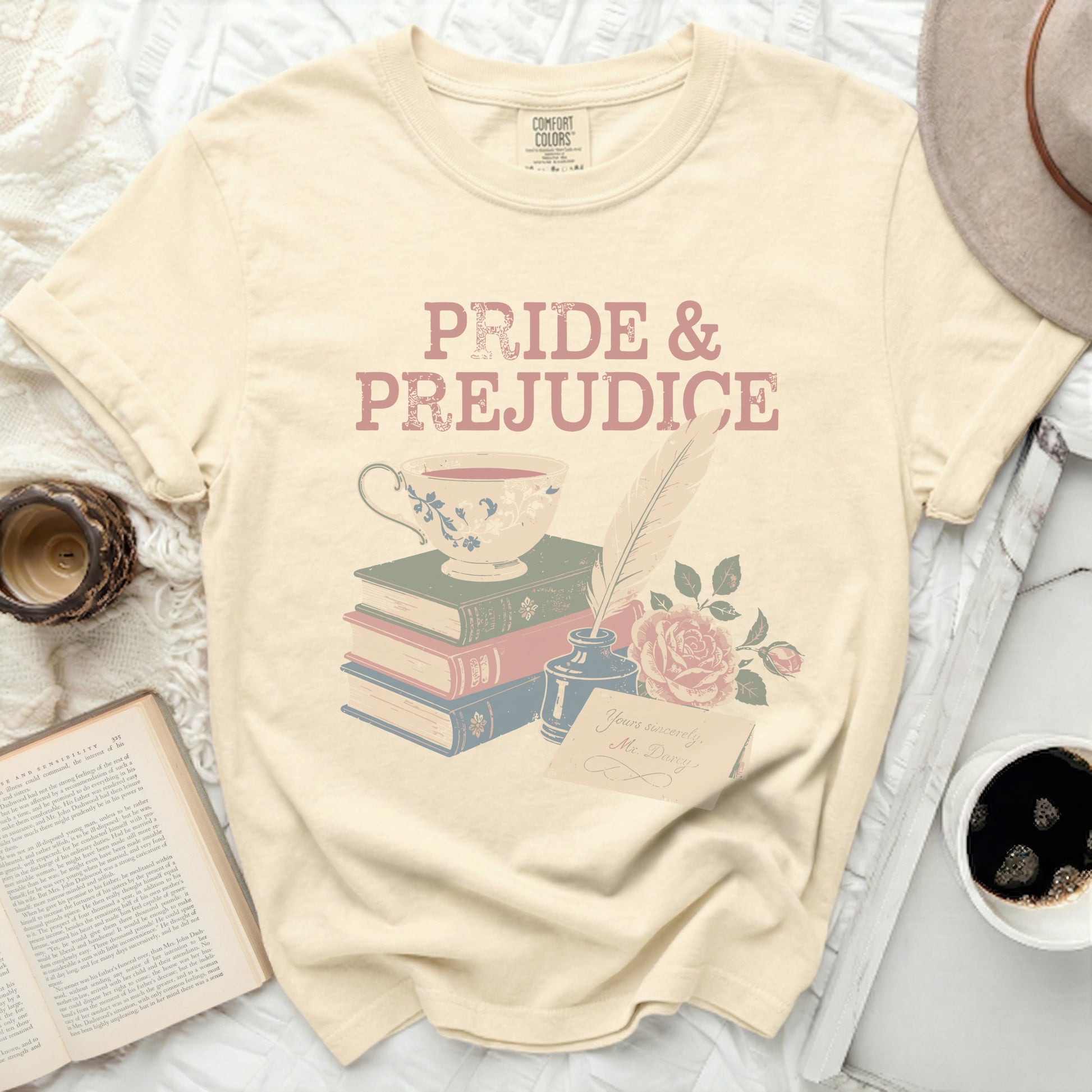 Cream t-shirt with Pride and Prejudice title, teacup, books, quill, ink, and rose.
