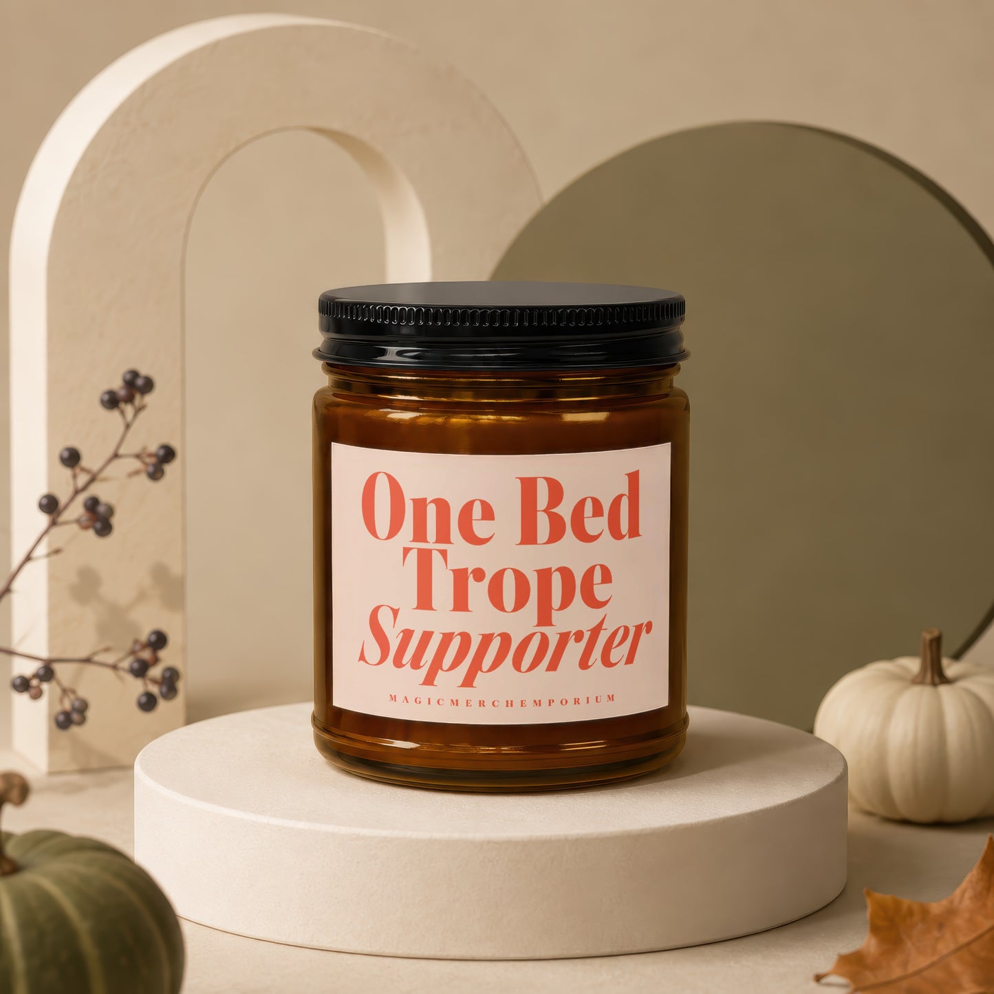 Amber jar candle with orange text reading "One Bed Trope Supporter" and "MAGICMERCH)EMPORIUM"