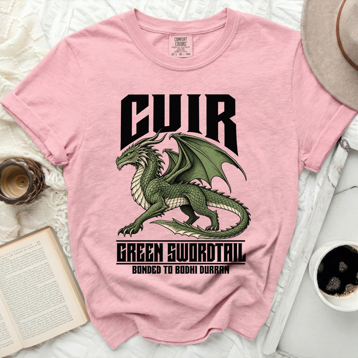 Pink t-shirt with a green dragon graphic and text "CUIR", "GREEN SWORDTAIL", and "BONDED TO BODHI DURRAN".