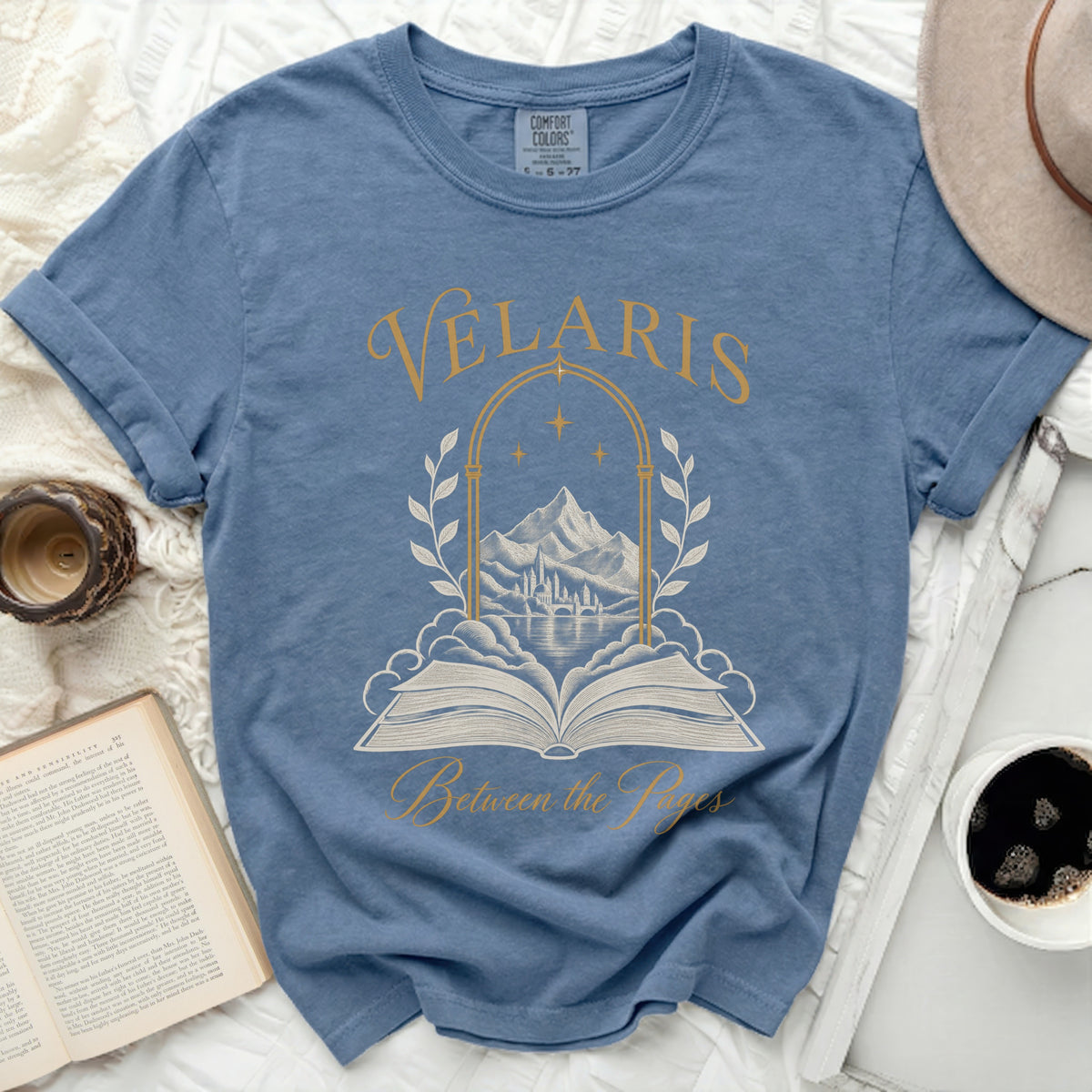 Blue t-shirt with gold text and design of an open book and castle.