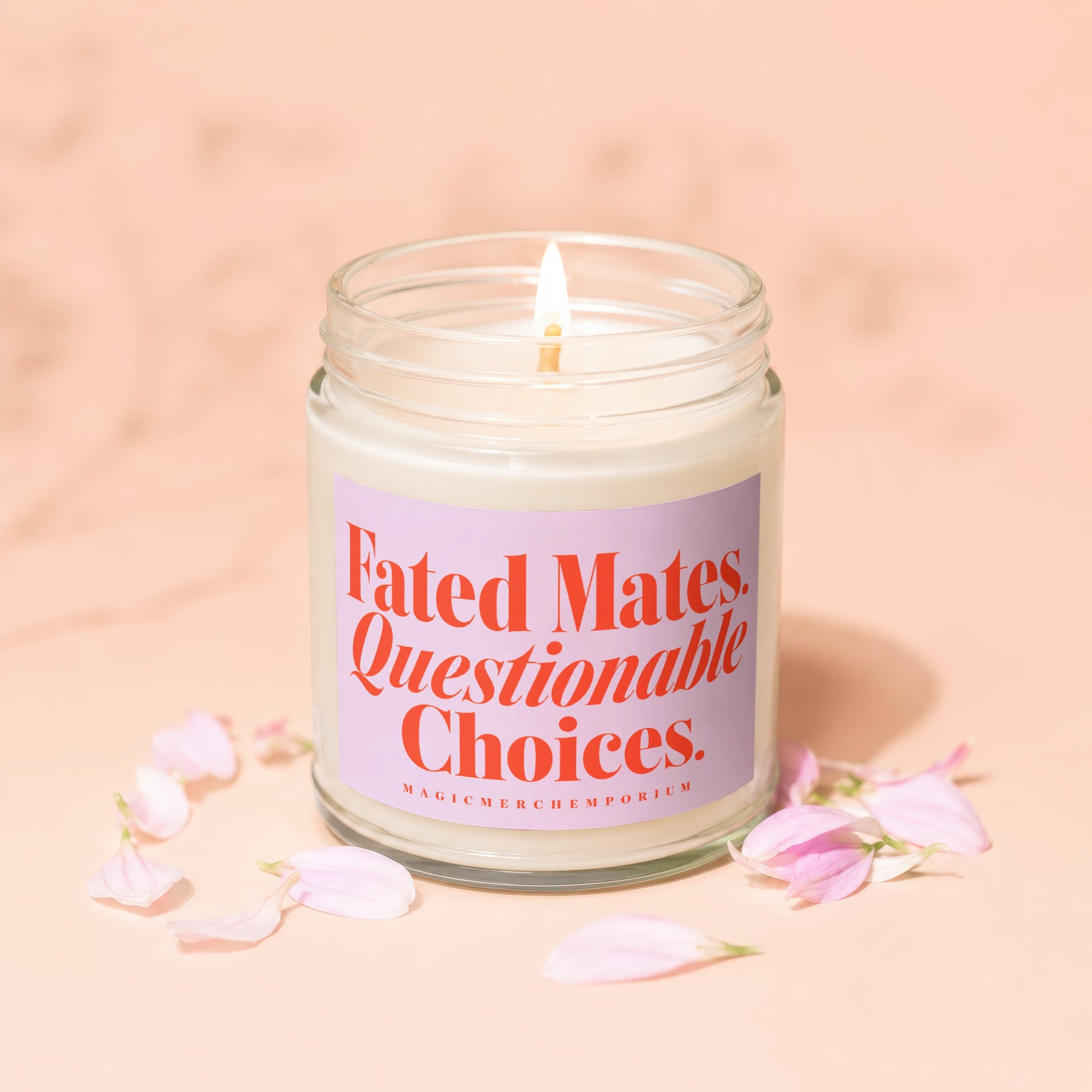 Glass candle with lit wick and pink label reading "Fated Mates. Questionable Choices."