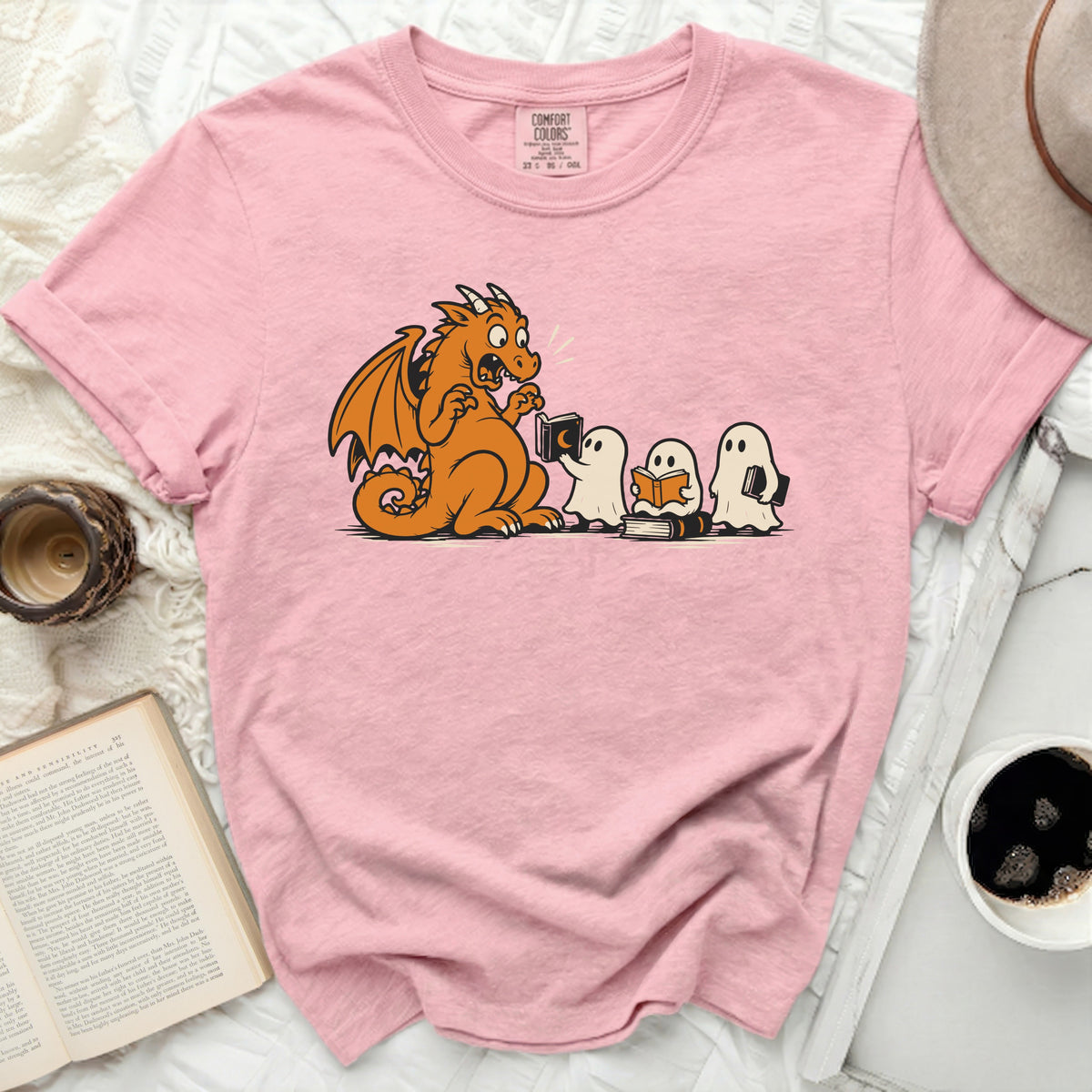 Pink t-shirt with cartoon of dragon reading to ghosts.
