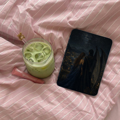 A glass of iced matcha latte, a Rhode lip balm, and a phone case with a fantasy art print adorn pink striped fabric.