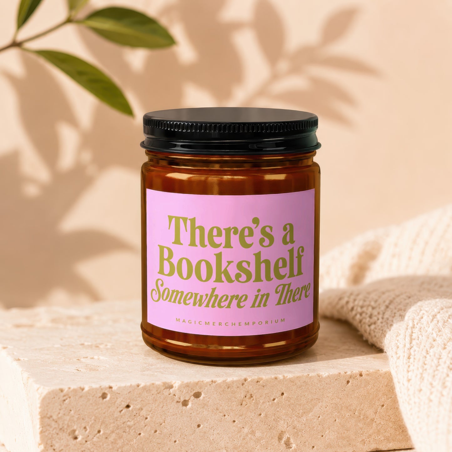 Brown glass candle with pink label reading "There's a Bookshelf Somewhere in There".