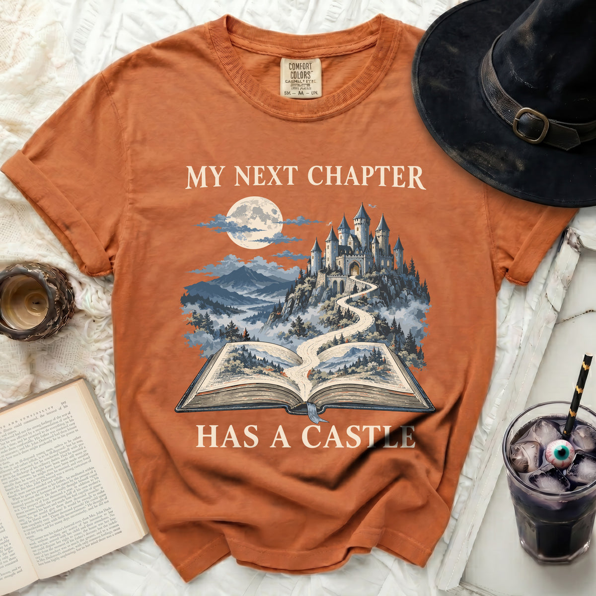 Orange t-shirt with "My Next Chapter Has A Castle" graphic.