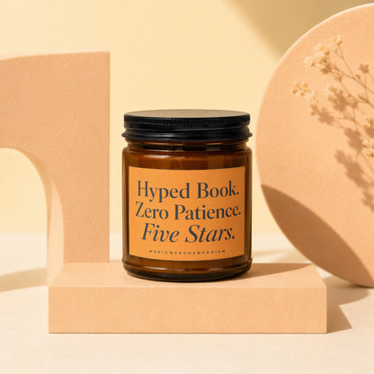 Amber glass candle with black lid, label reads "Hyped Book. Zero Patience. Five Stars."